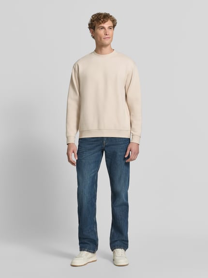 Mannenmodel draagt Slim Fit Pullover uit pure katoen 'TOM' van Selected, heren sweatshirt in beige met blauwe denim, volledig vooraanzicht.
