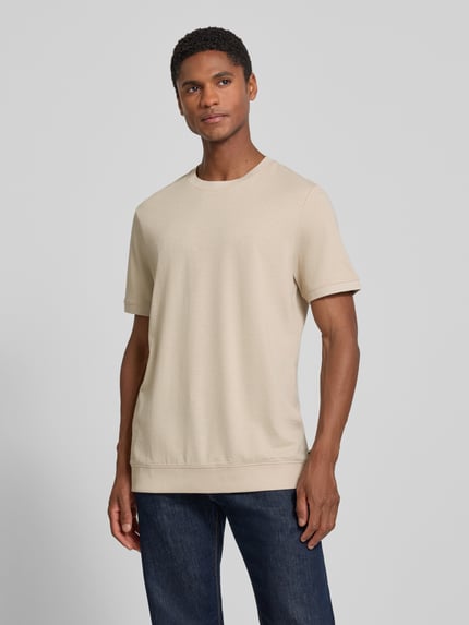Męski model nosi Regular Fit T-Shirt aus Baumwoll-Mix od s.Oliver RED LABEL w jasnobeżowym kolorze, gładka tekstura, Ganzkörperansicht von vorne.
