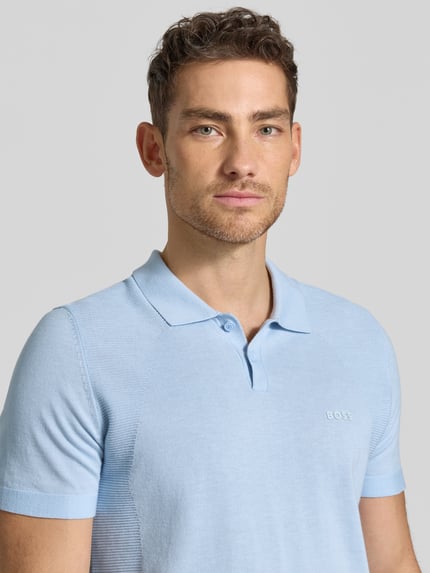 Männermodel trägt Poloshirt mit Logo Detail von BOSS Green in Hellblau, Optik: Unifarben, Passform: Regular-Fit, Logo-Print, Polokragen, Bodymapping-Struktur, Nahaufnahme Oberkörper.