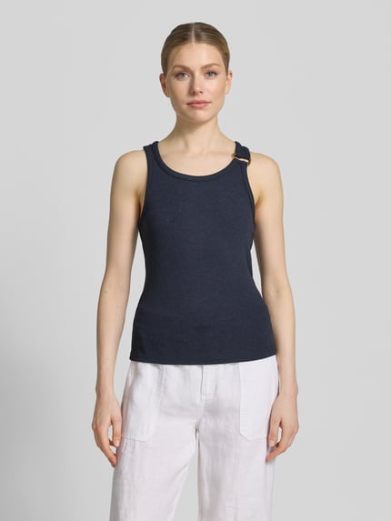 Frauenmodel trägt Regular Fit Tank Top aus Viskose-Mix Modell 'KIKI' von Vero Moda in Optik: Unifarben mit Zier-Applikation, U-Ausschnitt, breite Träger und Ripp-Materialverarbeitung; dunkler Blauton, glatte und gerippte Textur, Ganzkörperansicht von vorne.