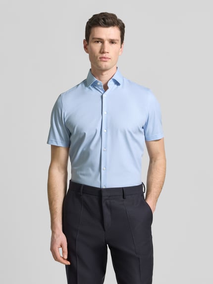 Mannenmodel draagt Slim Fit Business-Hemd in kortmouw ontwerp Modell 'Modern' van OLYMP Level Five, lichtblauw, katoenmengsel met stretch, kentkraag, knopenlijst, slim fit, voorkant gehele lichaam.