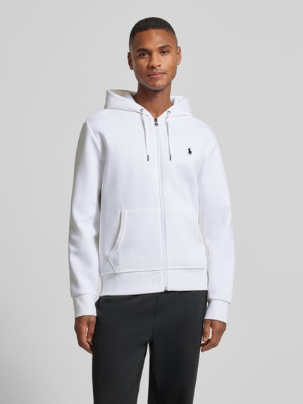 Męskimodel nosi Bluza rozpinana z kapturem od Polo Ralph Lauren, mieszanka bawełny i elastanu, krój regular fit, wpuszczane kieszenie, wyhaftowane logo, białe, gładka tekstura, długość tyłu 68 cm, długość rękawów 65 cm, całkowity widok z przodu.