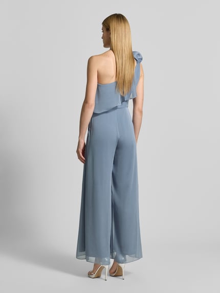 Frauenmodel trägt Regular Fit Jumpsuit mit floralem Zierbesatz von Swing in Hellblau, tailliert, mit Rüschenbesatz, Ganzkörperansicht Rückansicht. Rückenlänge bei Größe 36: 40 cm, Brustweite: 42 cm, Gesamtlänge: 150 cm, Innenbeinlänge: 80 cm, ärmelloses, asymmetrisches Design mit fließender Textur.