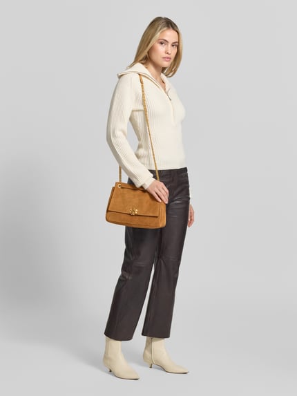 Frauenmodel trägt Crossbody Bag mit Tragehenkel von Tory Burch in Cognac-Braun mit Steppnähten, Metallkettenriemen, Ganzkörperansicht von vorne. Hauptfach mit Überschlag, Innenfach mit Reißverschluss, Größe ca. 29x21x11 cm.