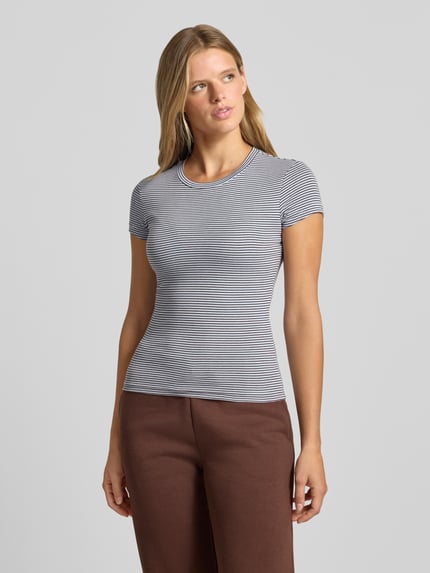 Frauenmodel trägt Skinny Fit T-Shirt aus Baumwoll-Mix von Gina Tricot mit feinen Streifen, Rundhalsausschnitt, Kurzarm, Ganzkörperansicht von vorne.