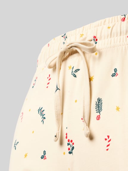 Frauenmodel trägt Slim Fit Pyjama-Hose aus reiner Baumwolle von Jake*s Casual, cremefarben mit buntem Muster, Nahaufnahme Hüftbereich.
