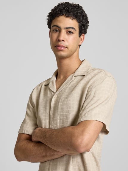 Männermodel trägt Regular Fit Freizeithemd aus Viskose-Leinen-Mix Modell 'LATHAM' von Only & Sons in Beige mit Strukturmuster, Nahaufnahme Oberkörper.