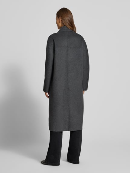 Frauenmodel trägt Regular Fit Mantel aus Woll-Mix mit Baumwoll-Anteil von MANGO, dunkelgraue Farbe, glatte Textur, Ganzkörperansicht Rückansicht. Modell PICAROL, Reverskragen, 2-Knopfleiste, Rückenlänge 113 cm, Schulterbreite 43 cm, Brustweite 54 cm, Ärmellänge 43 cm.