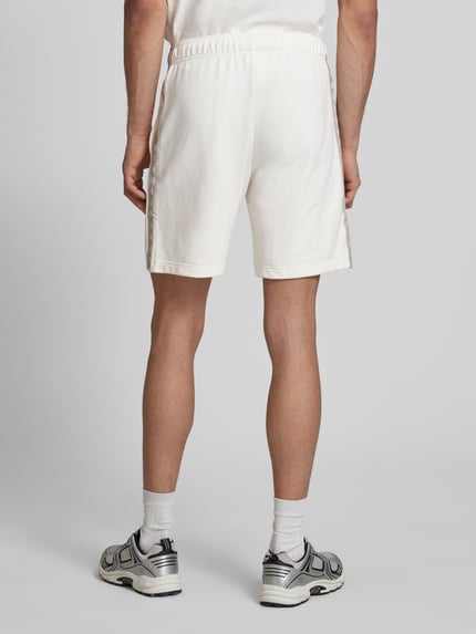 Männermodel trägt Shorts mit Logo und elastischem Bund von CHAMPION, weiß, Regular Fit, Baumwoll-Mix, Ganzkörperansicht Rückansicht.