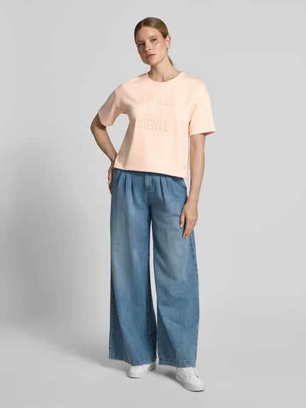 Vrouwenmodel draagt Regular Fit sweatshirt met viscose van monari in licht perzik, statement garnering, ronde hals, halflange mouwen, elastische materiaalmix, Ganzkörperansicht van voren.