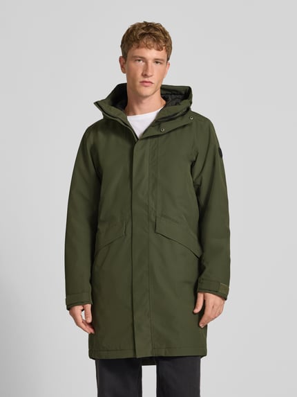 Męski model nosi zieloną parkę Didriksons Regular Fit Parka mit Kapuze Model 'Kenny' z wpuszczanymi kieszeniami, długa faktura, przód, długość tyłu w rozmiarze M: 99 cm, szerokość ramion w rozmiarze M: 48 cm, szerokość klatki piersiowej w rozmiarze M: 59 cm, długość rękawów w rozmiarze M: 72 cm, zdjęcie całej sylwetki z przodu.