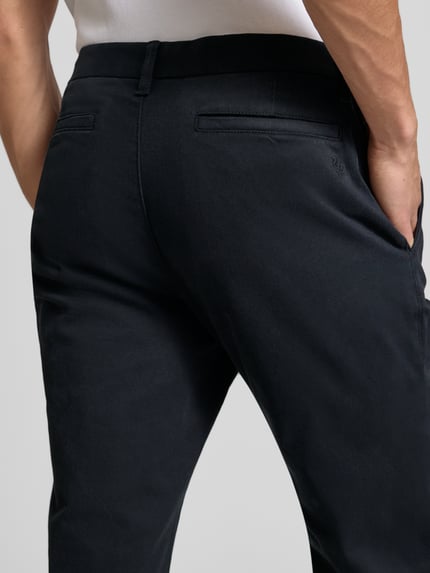 Männermodel trägt Schmale Chino mit gerader Silhouette und mittlerer Bundhöhe von REVIEW, Mix van katoen en elastaan, slim fit, strookzakken achter, kleur zwart, detailaufnahme Rückansicht