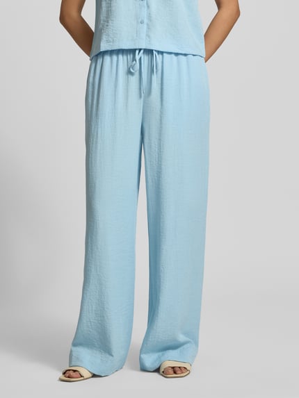 Frauenmodel trägt Straight Fit Hose aus Viskose-Mix Modell 'Daria' von MSCH Copenhagen in Hellblau mit elastischem Bund und Tunnelzug, Leinen-Viskose-Anteil, strukturierte Oberfläche, Nahaufnahme Oberkörper.