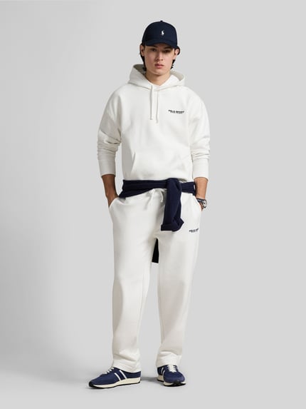Männermodel trägt Relaxed Fit Hoodie aus Baumwoll-Mix von Polo Ralph Lauren in Unifarben mit Label-Schriftzug, Ganzkörperansicht von vorne.