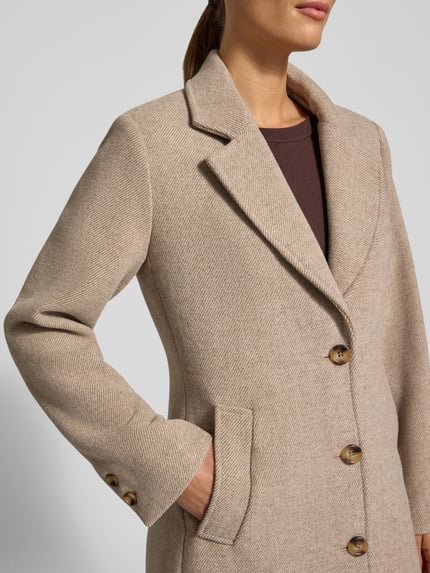 Kobiece model prezentuje płaszcz z mieszanki materiałów z dodatkiem wełny Model 'CAPPOTTO' od Liu Jo White, jasnobeżowy, wpuszczane kieszenie, listwa guzikowa, kołnierz z połami, krój regular fit, zbliżenie na górną część ciała.