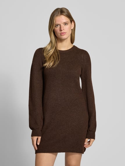 Frauenmodel trägt braunes Strickkleid mit Label-Detail von PIECES, weiche Textur, schlichtes Design, Nahaufnahme Oberkörper, Damen Freizeitkleid.