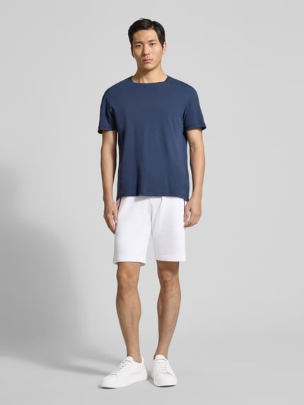 Männermodel trägt Shorts mit elastischem Bund von Christian Berg Men aus Baumwoll-Elasthan-Mix, Regular-Fit, Ganzkörperansicht von vorne. Eingrifftaschen mit Kontraststreifen, Tunnelzug, Bundweite bei Größe M 43 cm, Innenbeinlänge bei Größe M 23 cm.