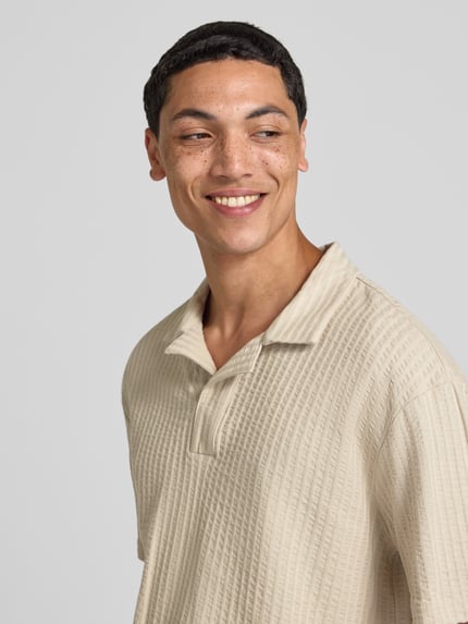 Männermodel trägt Relaxed Fit Poloshirt aus reiner Baumwolle Modell 'AUSTIN' von Only & Sons, Optik: Unifarben, gestreift, Seersucker, Nahaufnahme Oberkörper