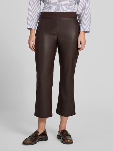 Frauenmodel trägt Flared Fit Hose in -Optik von Christian Berg Woman, braune Farbe, elastischer Bund, verkürzte Passform, Nahaufnahme Unterkörper.