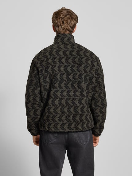 Männermodel trägt Fleecepullover mit Stehkragen und Reißverschluss von KARL KANI, Regular-Fit, Allover-Look, Rückenlänge 70 cm, Ganzkörperansicht Rückansicht.