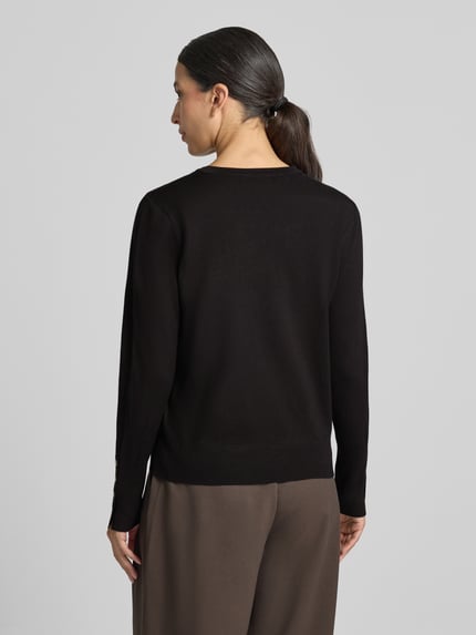 Frauenmodel trägt Strickpullover aus Viskose-Mix Modell 'KATIE' von FREE/QUENT, schwarze Farbe, glatte Textur, Ganzkörperansicht Rückansicht. Gerader Schnitt, elastische Abschlüsse, Knöpfe an den Ärmelabschlüssen, Rückenlänge 58 cm, Ärmellänge 66 cm.
