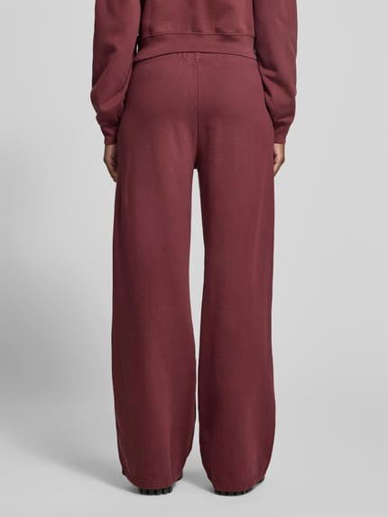 Frauenmodel trägt Regular Fit Sweathose mit Seitenschlitz von Anine Bing in Uni-Optik, Gummizug, Struktur, Nähte, Ganzkörperansicht Rückansicht.
