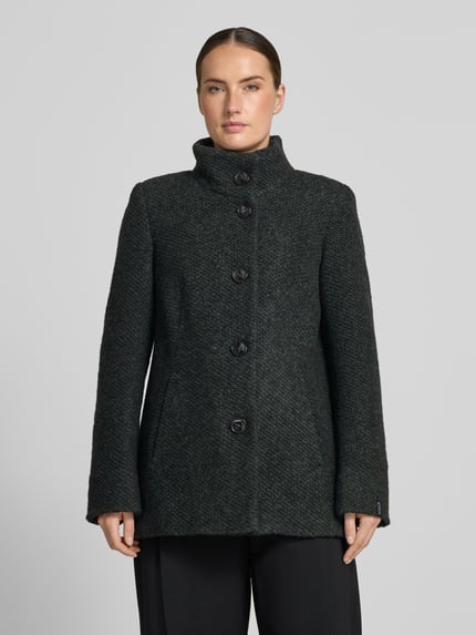 Frauenmodel trägt Jacke mit Stehkragen Modell 'JANINE' von Milo Coats, dunkles Material-Mix mit Schurwolle, Knopfverschluss, Eingrifftaschen, Ganzkörperansicht von vorne.