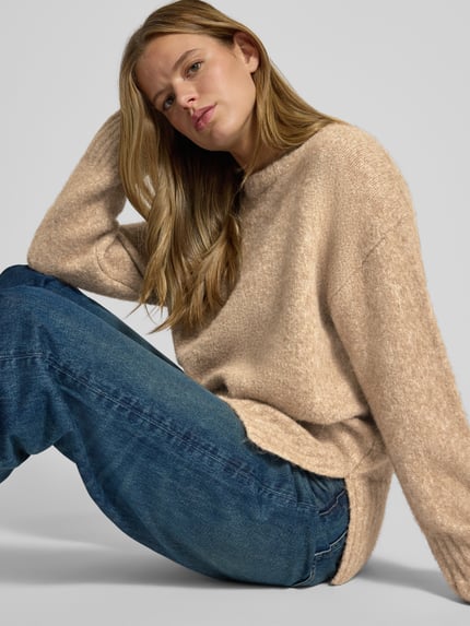 Frauenmodel trägt Pullover mit gerippten Abschlüssen von PIECES in Beige, langärmelig, unifarben, Longline Regular Fit, Nahaufnahme Oberkörper.