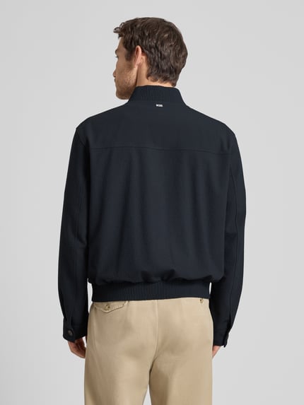 Männermodel trägt Regular Fit Blouson mit Baseball-Kragen Modell 'H-COMBO' von BOSS, dunkelblau, Seersucker, Optik:Allover-Muster, Ganzkörperansicht Rückansicht.