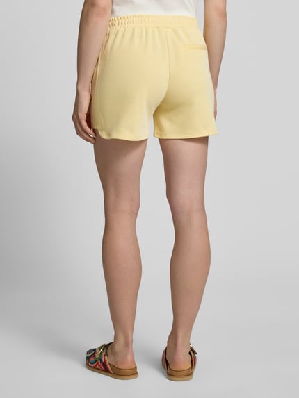 Frauenmodel trägt Shorts mit elastischem Bund Modell 'KATE PIQUE' von ICHI aus Baumwoll-Mix in Gelb, Regular-Fit, Ganzkörperansicht Rückansicht.