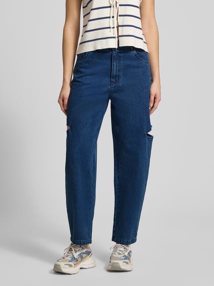 Kobiece modelka nosi Barrel Jeans mit seitlichen Cut Outs von Karo Kauer z bawełny, krój loose fit, 5 kieszeni, szerokość w rozmiarze S 38 cm, długość wewnętrzna nogawki 71 cm, zapięcie na guzik i zamek błyskawiczny, niebieski denim, wycięcia z boku, całkowity widok z przodu