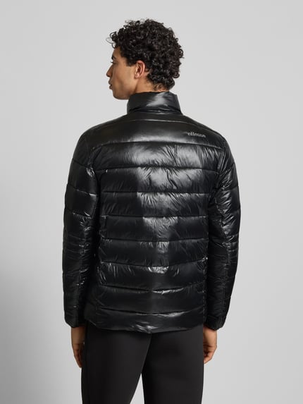 Männermodel trägt schwarze Steppjacke mit Stehkragen Modell 'ORSINI' von Ellesse, glatte Textur, Regular Fit, Ganzkörperansicht Rückansicht.