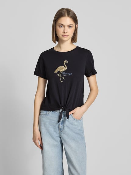 Vrouwenmodel draagt Regular Fit T-Shirt uit pure katoen model 'DORA LIFE' van Only, uni kleur, pailletten applicatie, knoopdetail, ronde hals, korte mouwen, detailopname bovenlichaam.