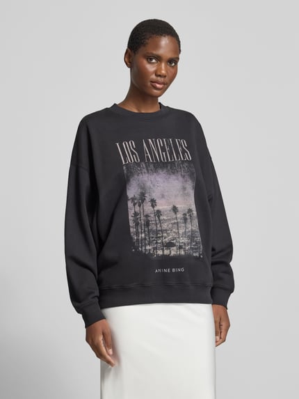 Frauenmodel trägt Sweatshirt mit Los-Angeles-Fotoprint von Anine Bing in mehrfarbiger Jersey-Optik, Motiv- und Logo-Prints, Rundhals, gerippte Abschlüsse, Ganzkörperansicht von vorne.