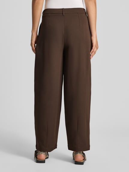 Frauenmodel trägt Barrel Fit Bundfaltenhose aus reiner Baumwolle Modell 'KIRSY' von ONLY in Braun, glatte Webstruktur, Ganzkörperansicht Rückansicht.