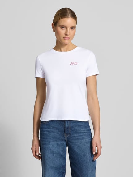 Kobiece model prezentuje Regular Fit T-Shirt aus reiner Baumwolle od Tom Tailor Denim, efekt: jednolity kolor, wyhaftowany napis, okrągły dekolt, krótki rękaw, wykończenie materiału: dżersej, materiał: bawełna, Ganzkörperansicht von vorne.