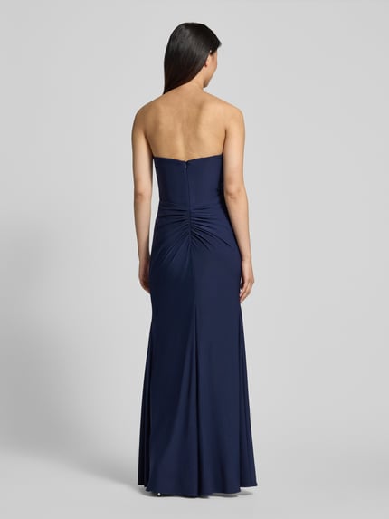 Frauenmodel trägt Slim Fit Abendkleid in Maxilänge mit Gehschlitz von Hey Kyla aus Elastischer-Material-Mix in Dunkelblau, Raffung, Schulterfrei, Ganzkörperansicht Rückansicht. Rückenlänge: 132 cm, Brustweite: 28 cm bei Größe 36.