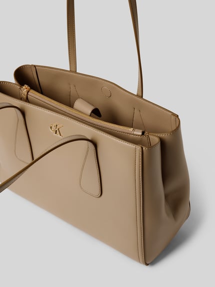 Produktfoto, Tote Bag mit Logo-Detail von CK Calvin Klein in Beige, geteiltes Hauptfach, Reißverschlussfach, schmale Schulterriemen, glatte Textur, Maße ca. 37 x 25 x 16 cm, Länge Schulterriemen 63 cm.