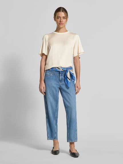 Frauenmodel trägt T-Shirt aus Viskose-Mix mit Rundhalsausschnitt von Comma in Creme, Gerader-Schnitt, 1/2-Arm, Rückenlänge 55 cm, Ganzkörperansicht von vorne.