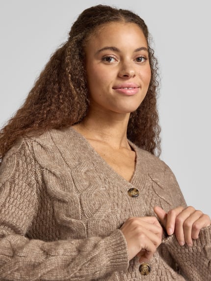 Frauenmodel trägt Cardigan mit Zopfmuster-Strickoptik von PIECES in melierter Strickoptik, V-Ausschnitt, Nahaufnahme Oberkörper.