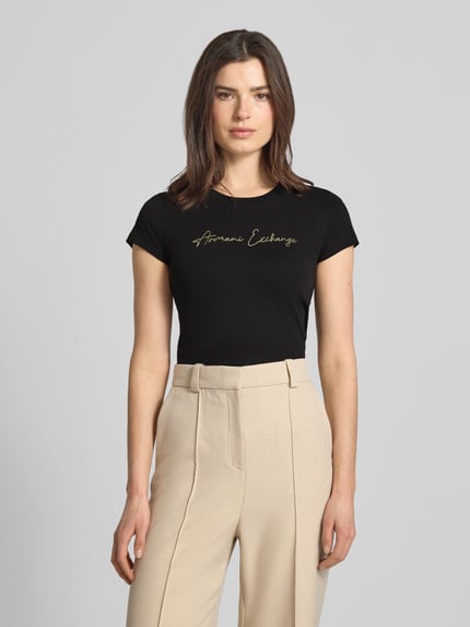 Frauenmodel trägt T-Shirt mit Logo und Rundhalsausschnitt von ARMANI EXCHANGE aus reiner Baumwolle, Slim Fit, Schwarz, Schriftzug vorn, Ganzkörperansicht von vorne