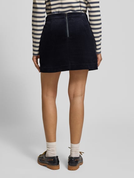 Vrouwenmodel draagt Cordrock in Minilänge van JAKE*S STUDIO WOMAN, donkerblauw corduroy, lichte A-lijn, siernaad, rugrits. Ganzkörperansicht Rückansicht.