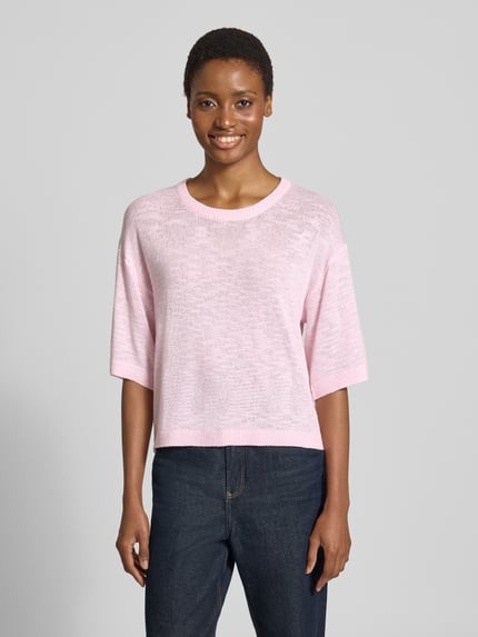 Frauenmodel trägt Relaxed Fit Pullover aus Viskose-Mix Modell 'Vicki' von FREE/QUENT in zartem Rosa, Struktur in Stick-Optik, Halbarm, Rundhals, semitransparente Textur, Damen Pullover, Ganzkörperansicht von vorne.