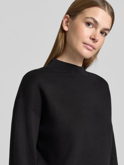 Frauenmodel trägt Pullover mit ausgestelltem Ärmelabschluss von JAKE*S WOMAN COLLECTION, unifarben matt in Schwarz, Strick, Nahaufnahme Oberkörper