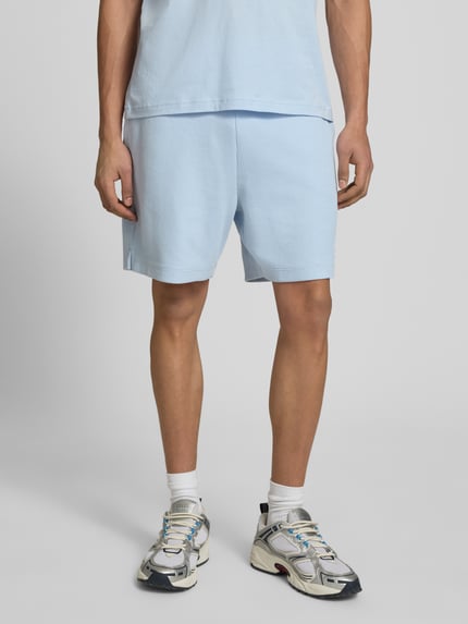 Mannelijk model draagt Regular Fit Sweatshorts aus Baumwoll-Mix Modell 'NUWAFFLO' van HUGO Blue, effen lichtblauw, katoenmix textuur, met label patch en elastische tailleband, zijzakken en achterzak, vooraanzicht close-up benen