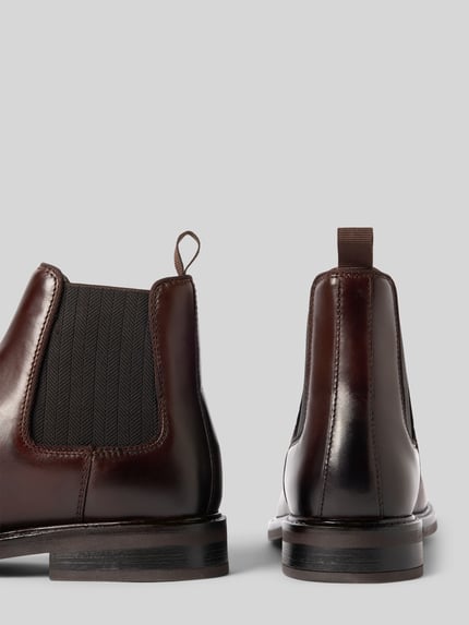 Produktfoto, Chelsea Boots mit seitlichen Stretcheinsätzen von GANT in Braun, Lederoptik, strukturierte Gummisohle, Logo-Schriftzug, Detailaufnahme.