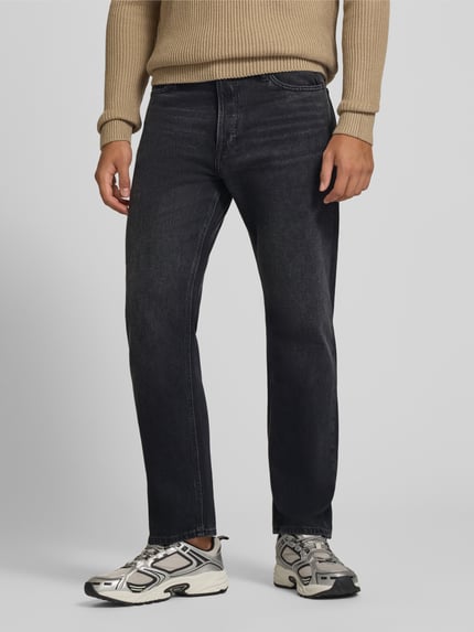 Mężczyznamodel nosi czarne jeansy Straight Fit z mieszanki bawełny z dodatkiem wełny escorial, model 'Chris' JACK & JONES, 5 kieszeni, zapięcie na guzik i zamek błyskawiczny, Szerokość w rozmiarze 32/32: 42 cm, Długość wewnętrzna nogawki: 76 cm, widok całej sylwetki z przodu.