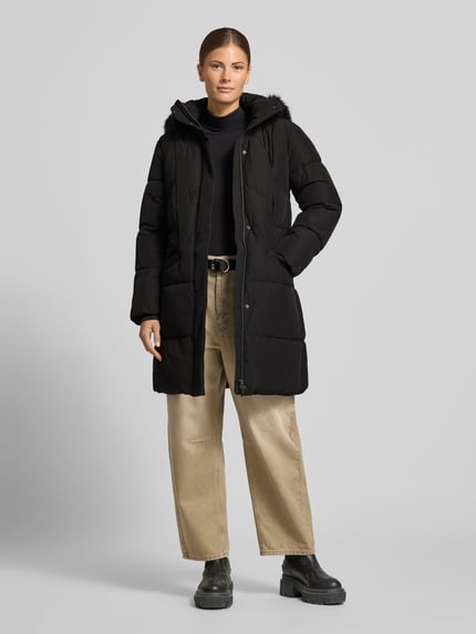 Frauenmodel trägt Steppmantel mit abnehmbarer Kapuze von JAKE*S WOMAN COLLECTION, schwarz, strukturierte Oberfläche, Longline, Ganzkörperansicht von vorne