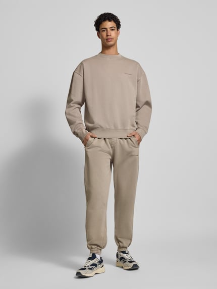 Männermodel trägt Sweatpants mit elastischem Bund von Pegador aus Baumwoll-Mix, Lockerer-Schnitt, Label-Stitching, Ganzkörperansicht von vorne.