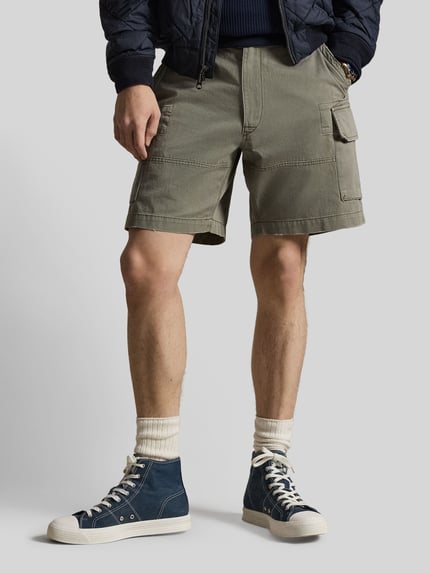 Männermodel trägt Relaxed Fit Cargoshorts aus reiner bawełna von Polo Ralph Lauren, efekt: jednolity kolor, wyhaftowane logo, szlufki na pasek, zapięcie na guzik i zamek błyskawiczny, wpuszczane kieszenie boczne, kieszenie z tyłu na guziki, kieszenie cargo, tkana faktura, ganzkörperansicht von vorne.